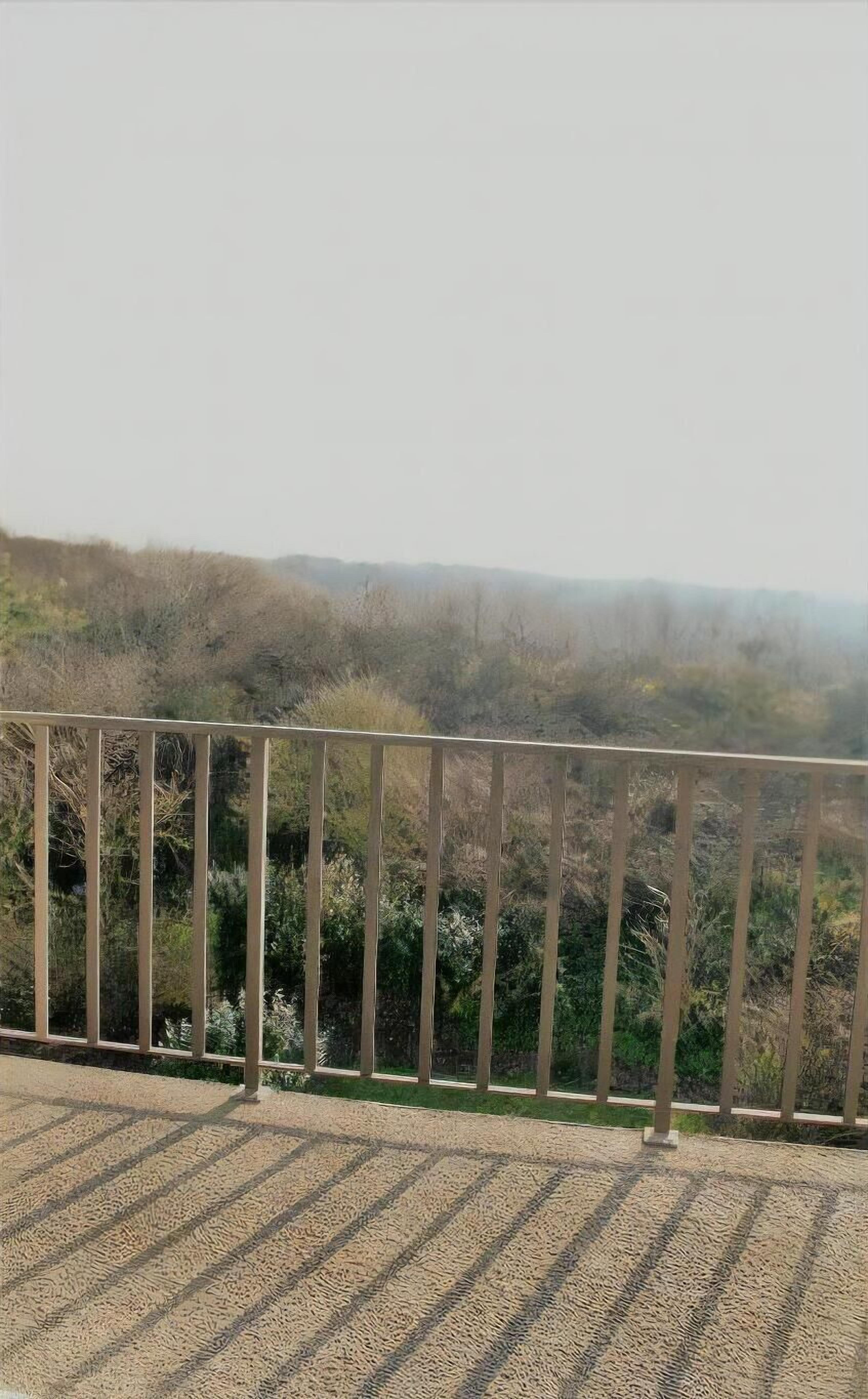 A balcony with a view of a hilly landscape.