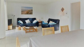Ein Wohnzimmer mit zwei Sofas, einem Couchtisch, einem Esstisch und einem Sessel.