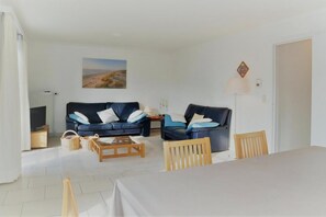 Un salon comprenant deux canapés, une table basse, une table à manger et une chaise.