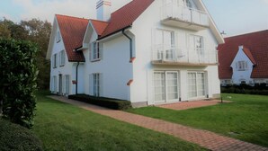 Ein zweistöckiges Haus mit rotem Dach, weißer Fassade und einem Ziegelweg, der zum Eingang führt.