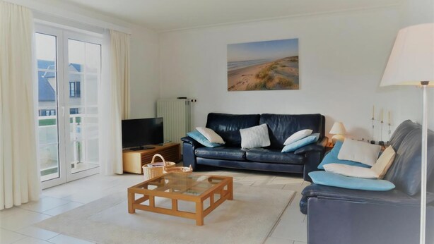 Ein Wohnzimmer mit Sofa, Couchtisch, Fernseher und einem Bild an der Wand.
