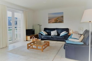 A living room with a sofa, a coffee table, a TV, and a painting on the wall.