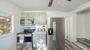Cocina compacta con electrodomésticos de acero inoxidable, incluyendo estufa, horno, microondas y refrigerador.