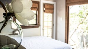 A room with a bed, a window with blinds, and a vase with a white flower. - The Yellow Treehouse by the Lake - NO CLEANING FEES!!! (Austin)