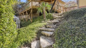 A multi-story wooden house with a stone staircase leading to a wooden deck. - The Yellow Treehouse by the Lake - NO CLEANING FEES!!! (Austin)