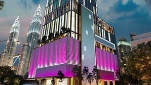 Un gratte-ciel moderne à la façade vitrée, entouré d’autres immeubles de grande hauteur.