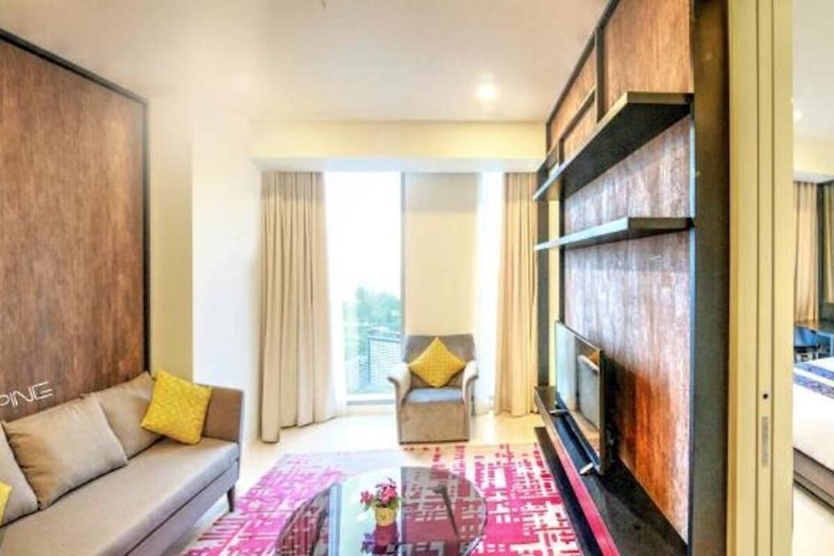 Ein Hotelzimmer mit einer Couch, einem Glastisch, einem Bett und Blick auf die Stadt.