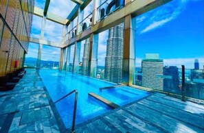Une piscine à débordement située sur le toit, offrant une vue sur la ville, une architecture moderne et un ciel dégagé.