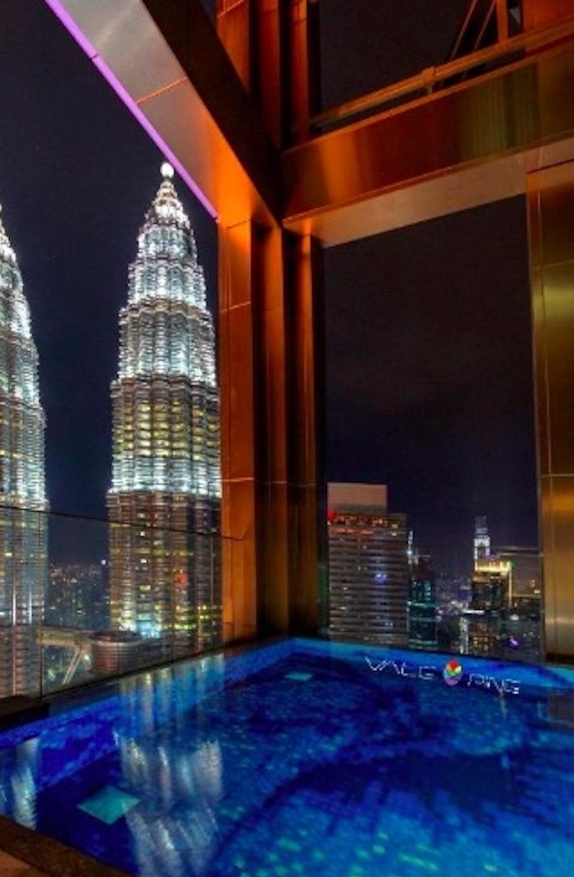 A modern interior with a view of the Petronas Towers at night.