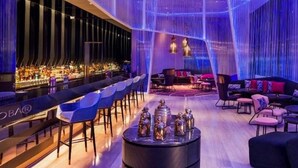Un bar moderne doté d’un long comptoir, de chaises bleues et d’un espace salon avec des canapés et des tables.