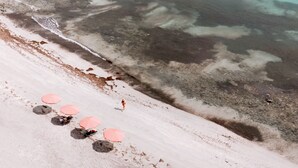A beach with clear turquoise water, a sandy shore, and a distant landmass. - CABN Kangaroo Island Ocean View Private Off Grid Luxury Accommodation (Willoughby)