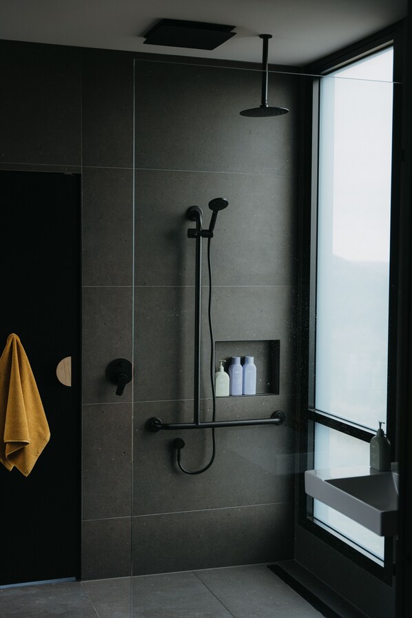 A modern bathroom with a shower, a towel rack, and a window.