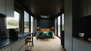 A modern bedroom with a large bed, a coffee machine, and a view of the outdoors. - CABN Kangaroo Island Ocean View Private Off Grid Luxury Accommodation (Willoughby)