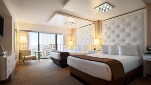 Ett hotellrum med två sängar, ett skrivbord, en stol och utsikt över staden.