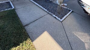 Una casa con garaje, entrada para vehículos y un pequeño jardín con plantas.