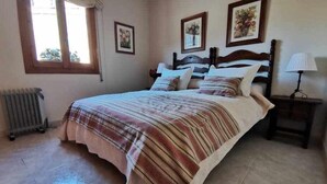 A bedroom with a bed, a nightstand, a radiator, and two framed pictures on the wall. - Casa Alfonso Toledo - Más que una casa, un hogar (Toledo)