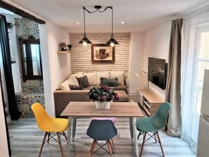 A modern living room with a wooden dining table, colorful chairs, a sofa, and a TV. - Casa Manuela I - More than a house, a home (Toledo)