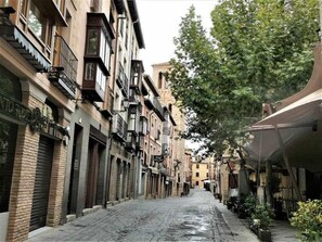 Een smalle, geplaveide straat met historische gebouwen, voorzien van balkons en luiken.