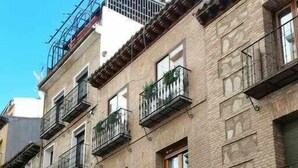 A multi-story building with balconies, a closed metal gate, and a visible door. - Casa Cervantes Toledo (Toledo)