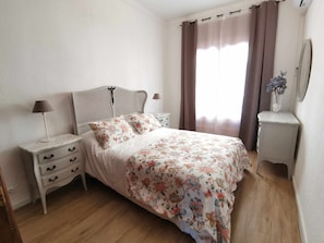 Une chambre à coucher comprenant un lit, des tables de chevet, une commode et un miroir.