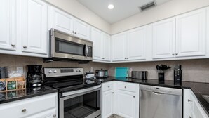 A modern kitchen with white cabinets, stainless steel appliances, and a black countertop. - Let's Spend Some Time Together (Wellington)