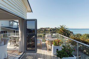 A balcony with a view of the sea, furnished with chairs and a table.