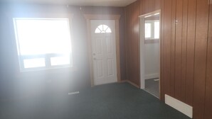 A hallway with a white door, a window, and wooden walls. - Retro Cowboy Country Style Great Ranchhand Worker (Bethune)