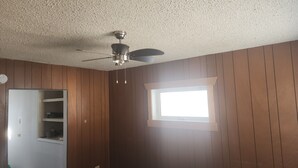 A room with wooden paneling, a ceiling fan, a window, and a door leading to a closet. - Retro Cowboy Country Style Great Ranchhand Worker (Bethune)