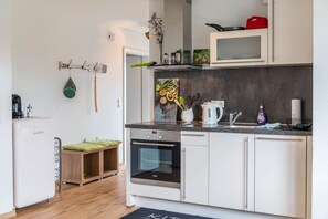 A modern kitchen with white cabinets, a built-in oven, a microwave, and a sink. - Apartment 'Turmgarten' with Mountain View, Private Terrace, and Wi-Fi (Überlingen)