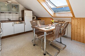 Une cuisine dotée d’une lucarne, de meubles blancs et d’une table à manger entourée de chaises en osier.