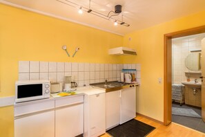 Une cuisine compacte équipée d’un four à micro-ondes, d’un grille-pain, d’un évier et de placards.