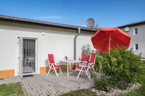 Une terrasse avec une table et des chaises, une antenne parabolique et un parasol rouge.