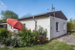 Ein eingeschossiges Gebäude mit Satellitenschüssel, kleinem Fenster und einem roten Regenschirm.