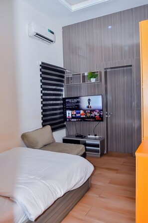 Una camera da letto moderna con un letto, una TV a muro, un armadio e un condizionatore.