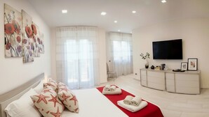 Una habitación de hotel con cama, televisión, escritorio y ventana con cortinas.