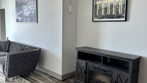 Una sala de estar moderna con un sofá gris, un mueble de entretenimiento de madera oscura y dos cuadros en la pared.