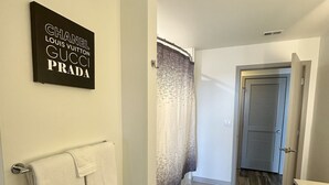 Un pasillo con un perchero, un cartel en la pared, una cortina estampada y una puerta.
