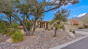 A building with a Mediterranean-style facade, surrounded by a landscaped garden with various plants and a gravel pathway. - El Conquistador/Golf+Mnt+LakesVIEWS/Sleeps4 (Oro Valley)