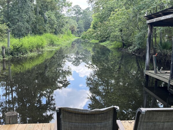A wooden dock extending over a calm river, surrounded by lush greenery and trees. - Madisonville near New Orleans Bamboo Bayou Cottage (Madisonville)