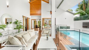A modern interior with a pool, white furniture, and wooden accents. - 54 Ocean Drive Palm Cove (Palm Cove)