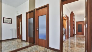 A hallway with stone flooring, wooden doors, and a radiator.