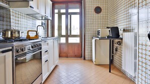 A kitchen with a stove, oven, refrigerator, and a door leading outside.