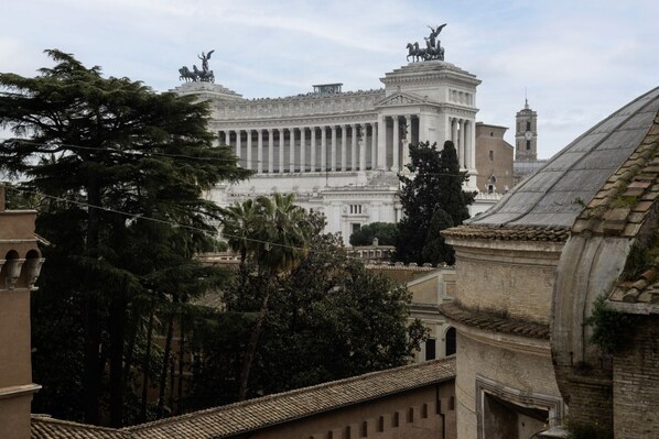 A grand building with classical architecture, including columns and statues, surrounded by trees and other buildings.