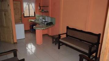 A small apartment with a kitchen area, a dining table, and a bench.