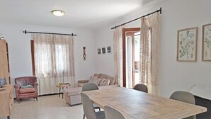 Een ruime eethoek met een houten tafel en stoelen, een bank en een fauteuil.