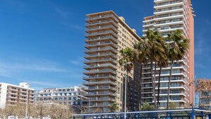 Un hôtel de grande hauteur doté de nombreux balcons, un ciel d’un bleu éclatant et des palmiers.