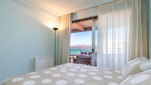 Une chambre à coucher comprenant un lit, une table de chevet, une lampe et donnant sur un balcon avec une table et des chaises.