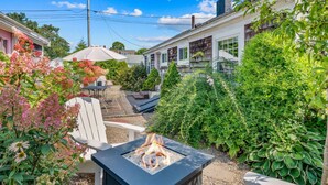 A backyard with a fire pit, outdoor furniture, and lush greenery. - Hosting and Helping Other making Memories managed by Itrip Property Management (Barnstable)