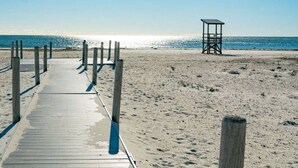 A wooden boardwalk leading to a lifeguard tower on a sandy beach with the ocean in the background. - Hosting and Helping Other making Memories managed by Itrip Property Management (Barnstable)