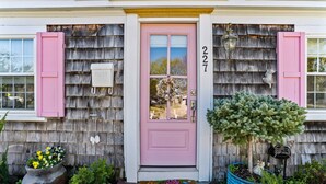 A house with a pink door, number 227, and a mailbox on the wall. - Hosting and Helping Other making Memories managed by Itrip Property Management (Barnstable)